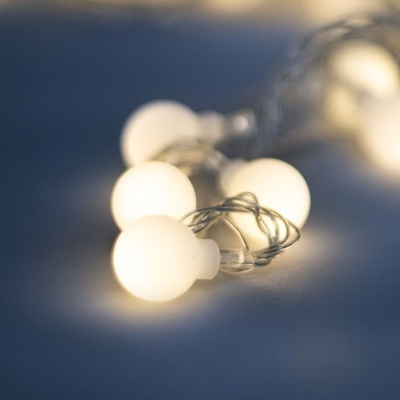 Cordão de luzes com lâmpadas redondas brancas quentes sobre superfície azul