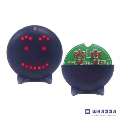 Dispositivo eletrônico redondo azul escuro com LEDs formando um rosto sorridente e placa eletrónica visível no verso