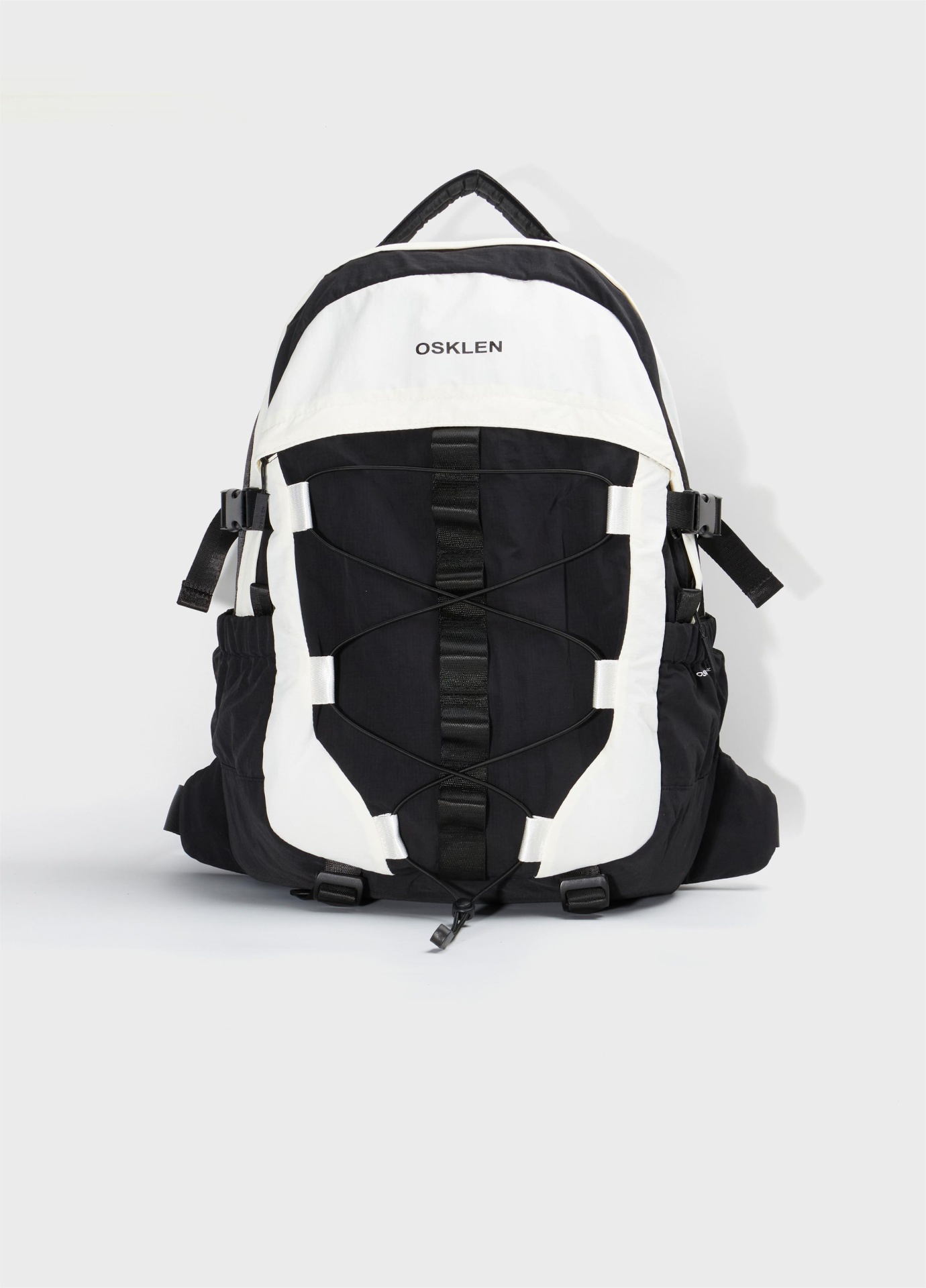 Mochila Nylon Superlight Osklen Mochila preta e branca com cordões elásticos frontais e logo OSKLEN