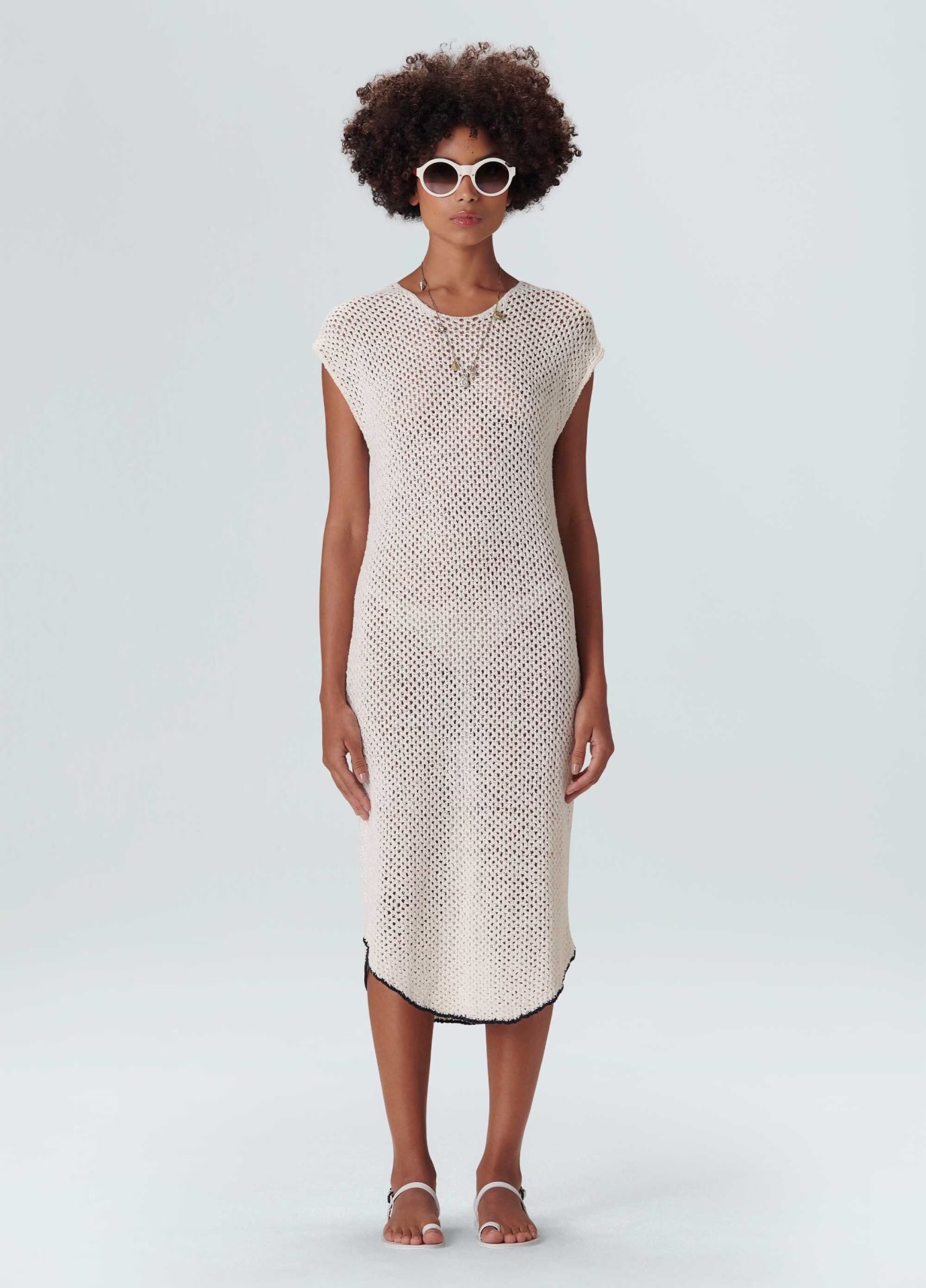 Vestido Regata Tricot Tela Osklen Modelo com vestido de malha crochet bege claro e óculos de sol brancos