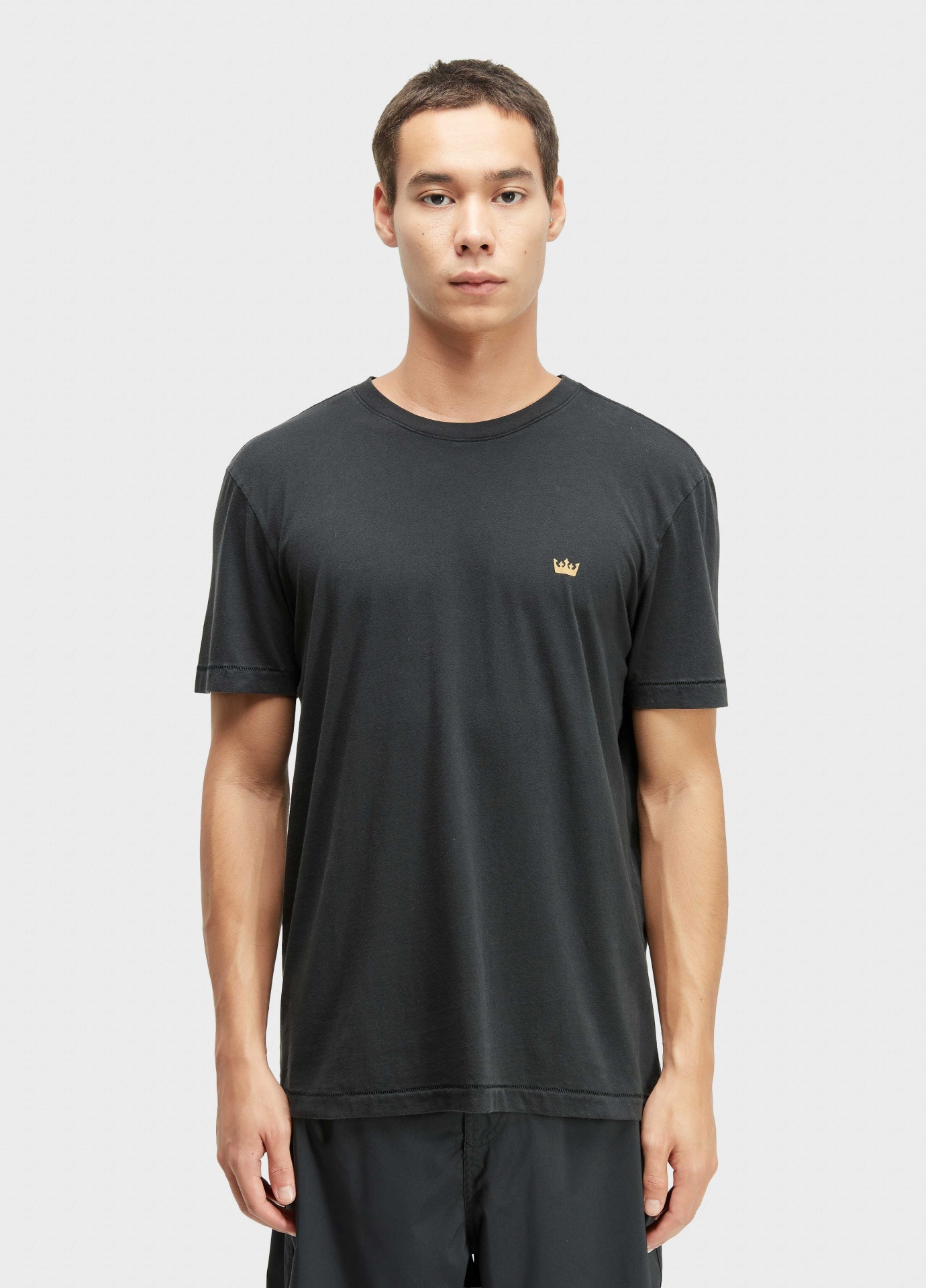 T-shirt Soft Used Gold Crown Osklen Homem com t-shirt preta e calças pretas, em fundo branco.