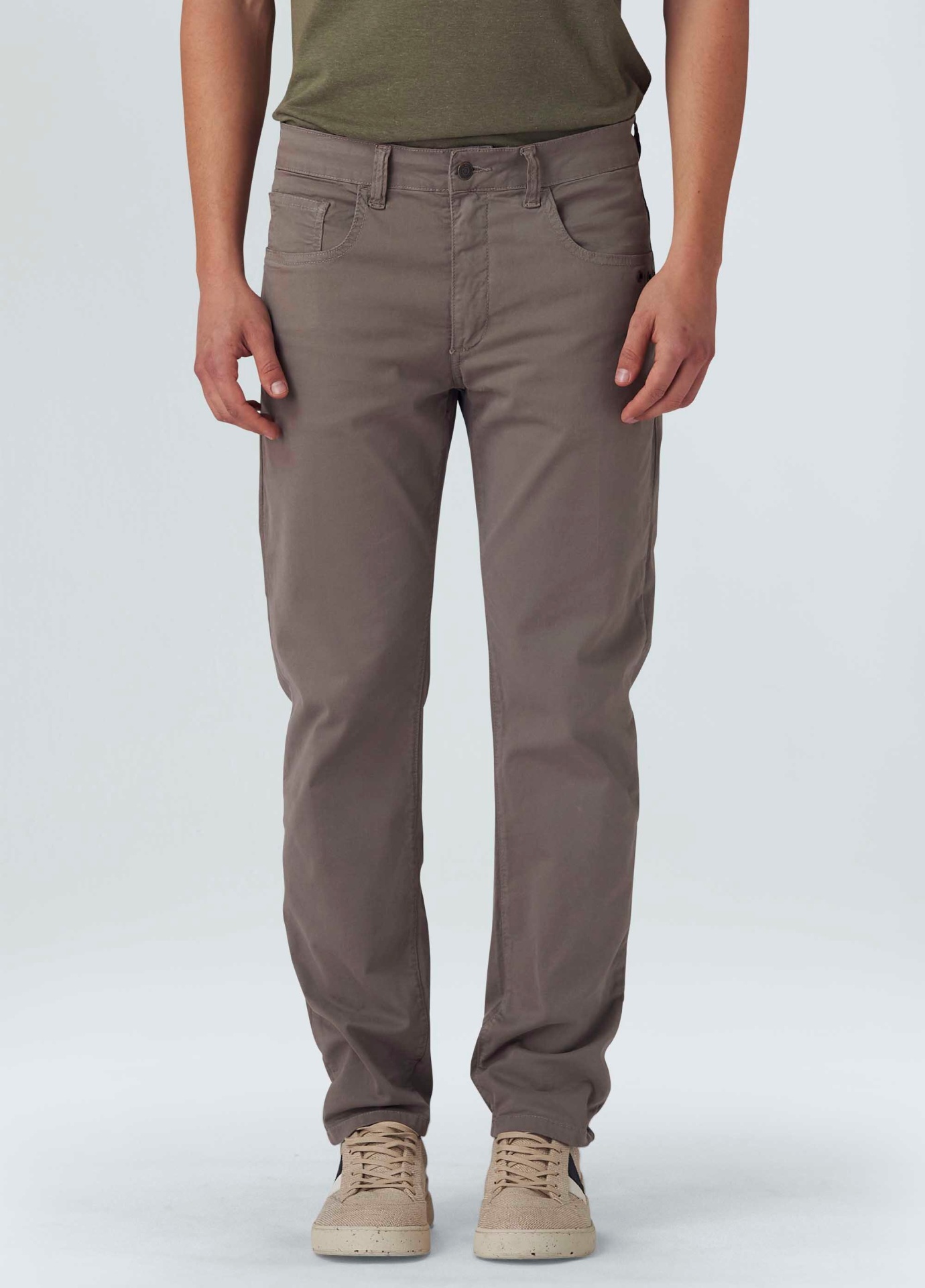 Calças cinza castanho com corte reto, tecido liso, usadas com sapatos bege e t-shirt verde.