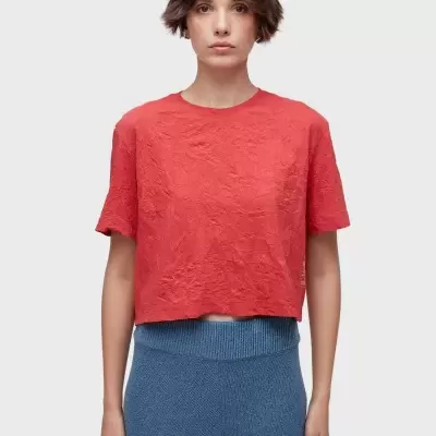 Top vermelho texturizado e calças de malha azuis em fundo branco