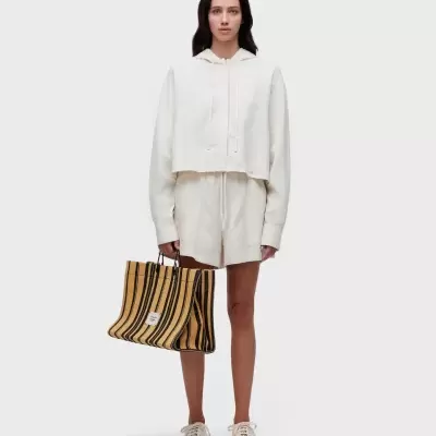 Mulher com conjunto creme e mala listrada