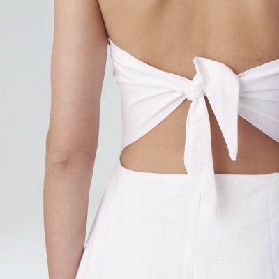Detalhe traseiro de vestido ou top branco com nó no meio das costas.