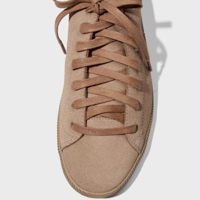 Ténis castanho de camurça com atacadores e sola castanha, sobre fundo cinza claro