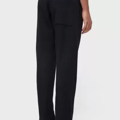 Calças pretas com bolso traseiro e sandálias pretas.