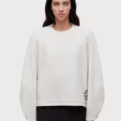 Sweatshirt branca de manga comprida com calções pretos e faixa branca, modelo em fundo cinza claro.