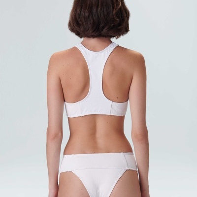 Modelo de costas a usar biquini branco texturizado com top desportivo e cuecas clássicas.