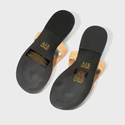 Solas pretas de sandálias com tiras bege trançadas vistas de baixo