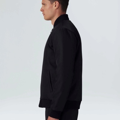 Homem de perfil a usar casaco preto de tecido liso com colarinho alto