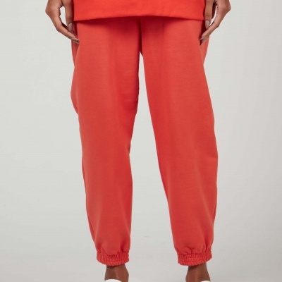 Calças cor de coral com bainha elástica e sapatos brancos