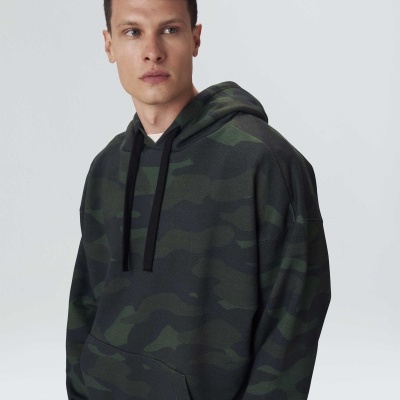 Homem a usar sweatshirt com capuz camuflado verde e preto, com cordões pretos.