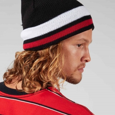 Gorro de malha preto com riscas brancas e vermelhas em fundo cinza