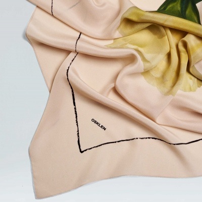 Lenço cor de rosa claro com flor amarela e verde e texto OSKLEN