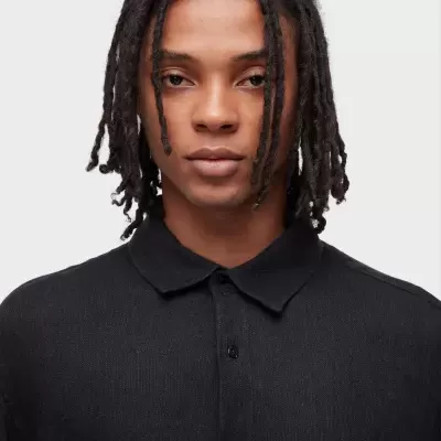 Homem com camisa preta de tecido texturizado com gola e botões.