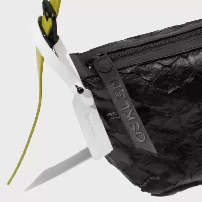 Mala preta enrugada com alças amarelo e branco com texto OSKLEN