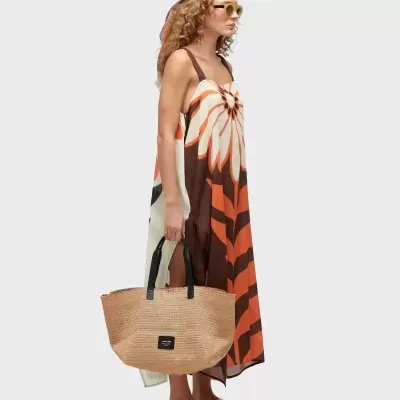 Mulher com vestido maxi floral, lenço de cabeça, óculos de sol, sandálias castanhas e mala de palha