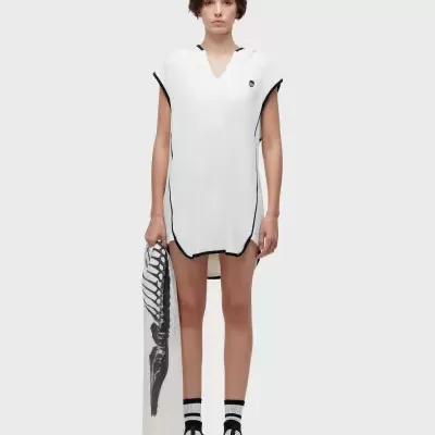 Mulher com vestido curto branco e toalha estampada em fundo branco