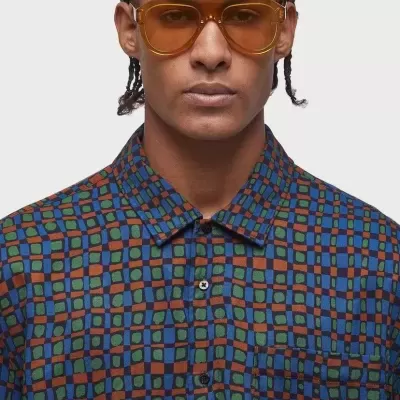 Camisa de padrão geométrico colorido e óculos de sol castanhos em modelo