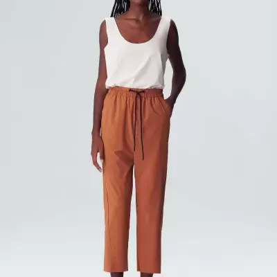 Modelo a usar calças ferrugem e top branco com sapatos baixos