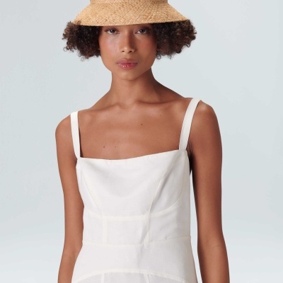 Mulher com vestido branco e chapéu de palha bege