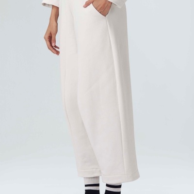 Calças largas brancas com bolso lateral e sapatilhas desportivas laranja.