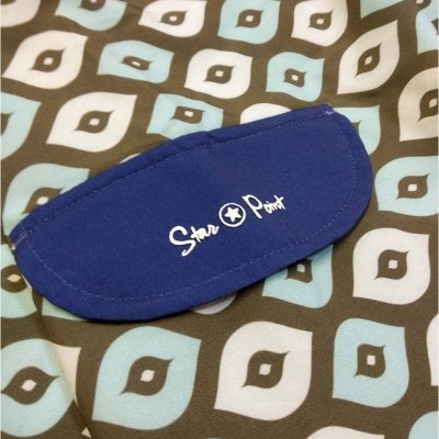 tecido com padrão geométrico nas cores azul claro, branco e castanho com estojo azul escuro com texto branco