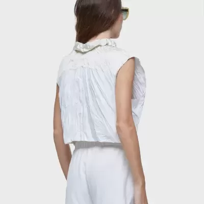 Blusa branca sem mangas com gola de folhos vista de costas.