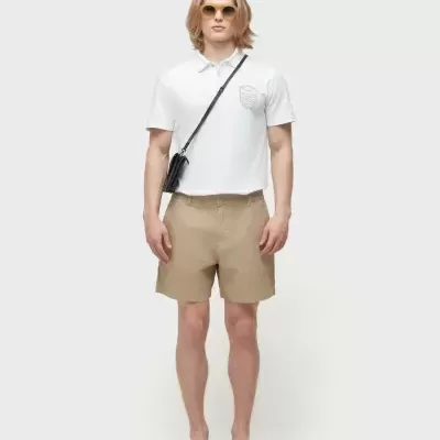 Homem com roupa casual clara e acessórios pretos sobre fundo branco