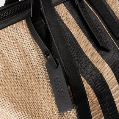 Mala riscada preta e bege com etiquetas em pele preta