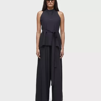 Conjunto feminino preto com top sem mangas, calças largas, ténis brancos e óculos escuros