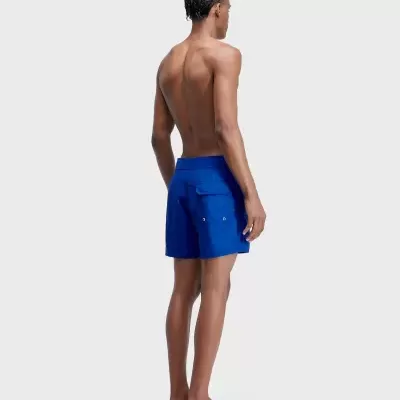Shorts de banho azuis com bolso traseiro usados por homem em fundo cinza