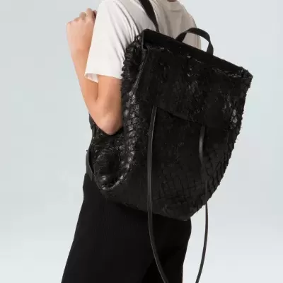 Mochila preta trançada usada por mulher com roupa clara