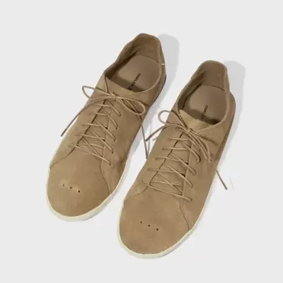 Ténis de camurça bege da marca OSKLEN com atacadores e solado branco sobre fundo branco.