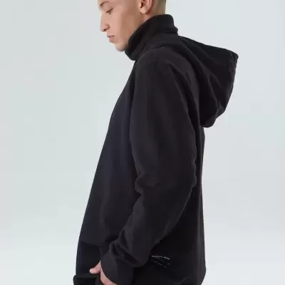 Homem com hoodie preto e calças pretas com riscas brancas, de perfil