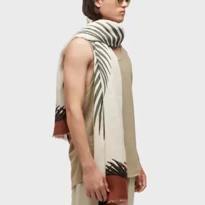 Modelo com lenço bege estampado, camiseta sem mangas bege e óculos de sol castanhos