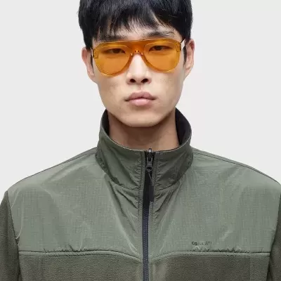 Homem com camisola verde escura e óculos de sol amarelos