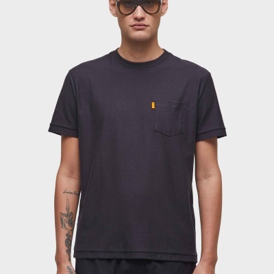 Homem com t-shirt preta de manga curta e bolso no peito com etiqueta amarela, óculos de sol castanhos e calções pretos.