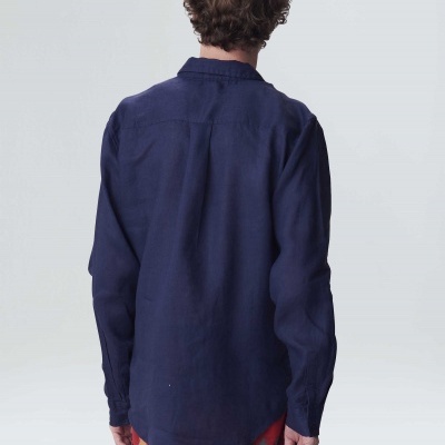 Homem de costas com camisa azul escura e calções coloridos com padrão abstrato.