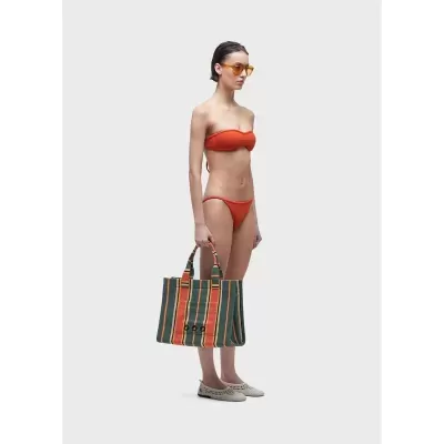 Mulher com bikini laranja e bolsa às riscas verticais