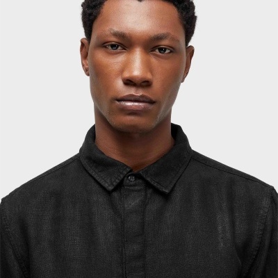 Homem com camisa preta de algodão com gola clássica.