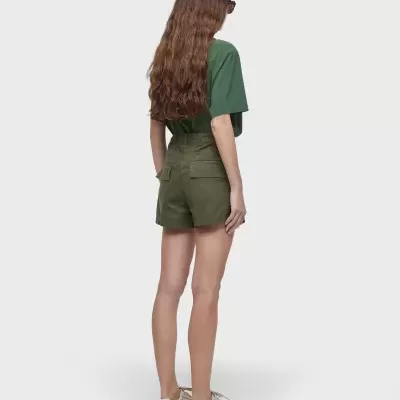 Mulher de costas com t-shirt verde, calções verde-oliva e sapatilhas brancas em fundo branco.