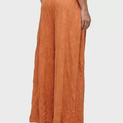 Calças largas laranja com padrão floral texturizado e cintura elástica, vistas de costas.