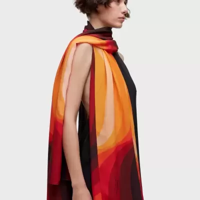 Echarpe longa colorida em tons de vermelho, laranja e amarelo em modelo com vestido preto