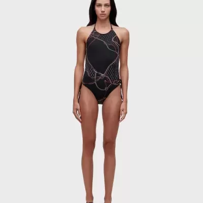 Mulher com fato de banho preto com padrão geométrico colorido e sandálias pretas