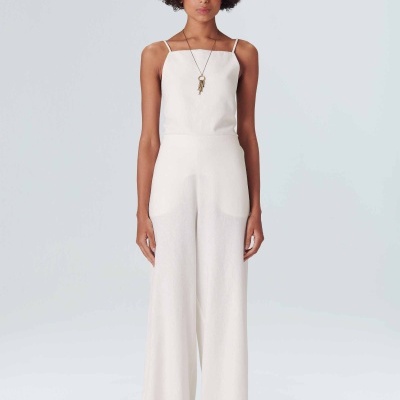 Macacão branco de alças finas com bolsos, modelo em fundo cinza claro