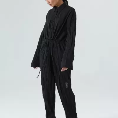 Macacão preto com cordão ajustável usado por modelo em fundo cinza