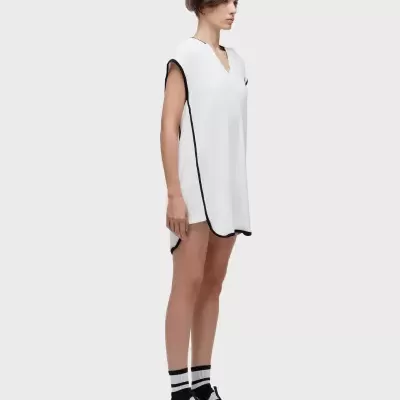 Vestido branco com acabamento preto e corte largo usado por mulher em fundo cinza