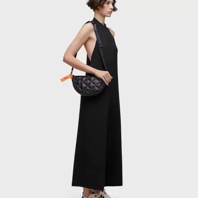 Mulher com vestido preto e bolsa preta acolchoada